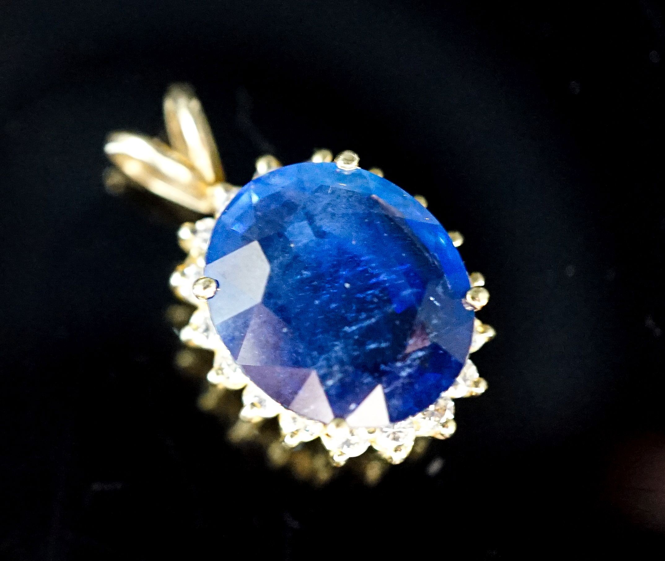 A yellow metal mounted sapphire and diamond set oval cluster pendant, 23mm, gross 4.6 grams.